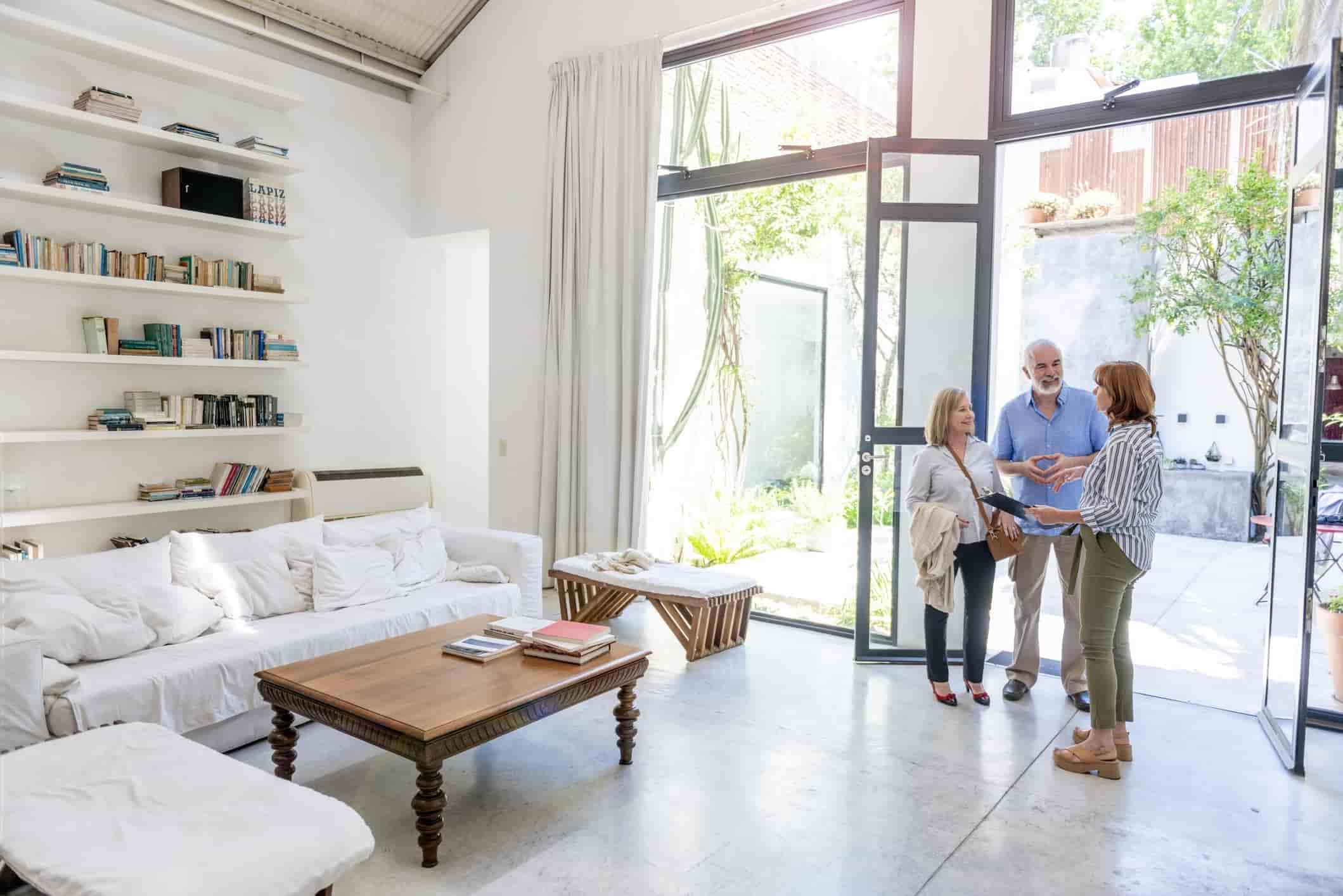 US real estate agent showing house to a couple and explaining rent income tax obligations. 