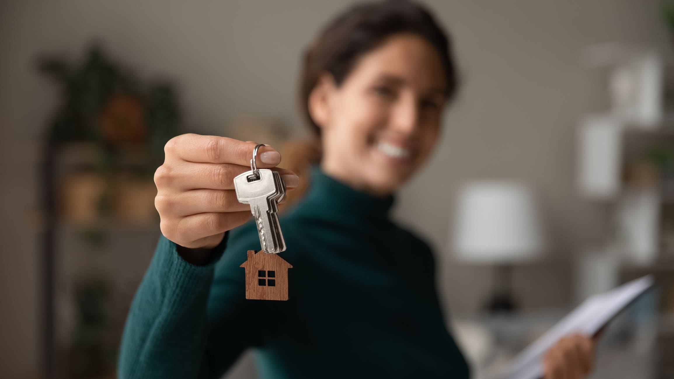 Close up focus on keys, smiling woman Real Estate Agent renting property in Poland