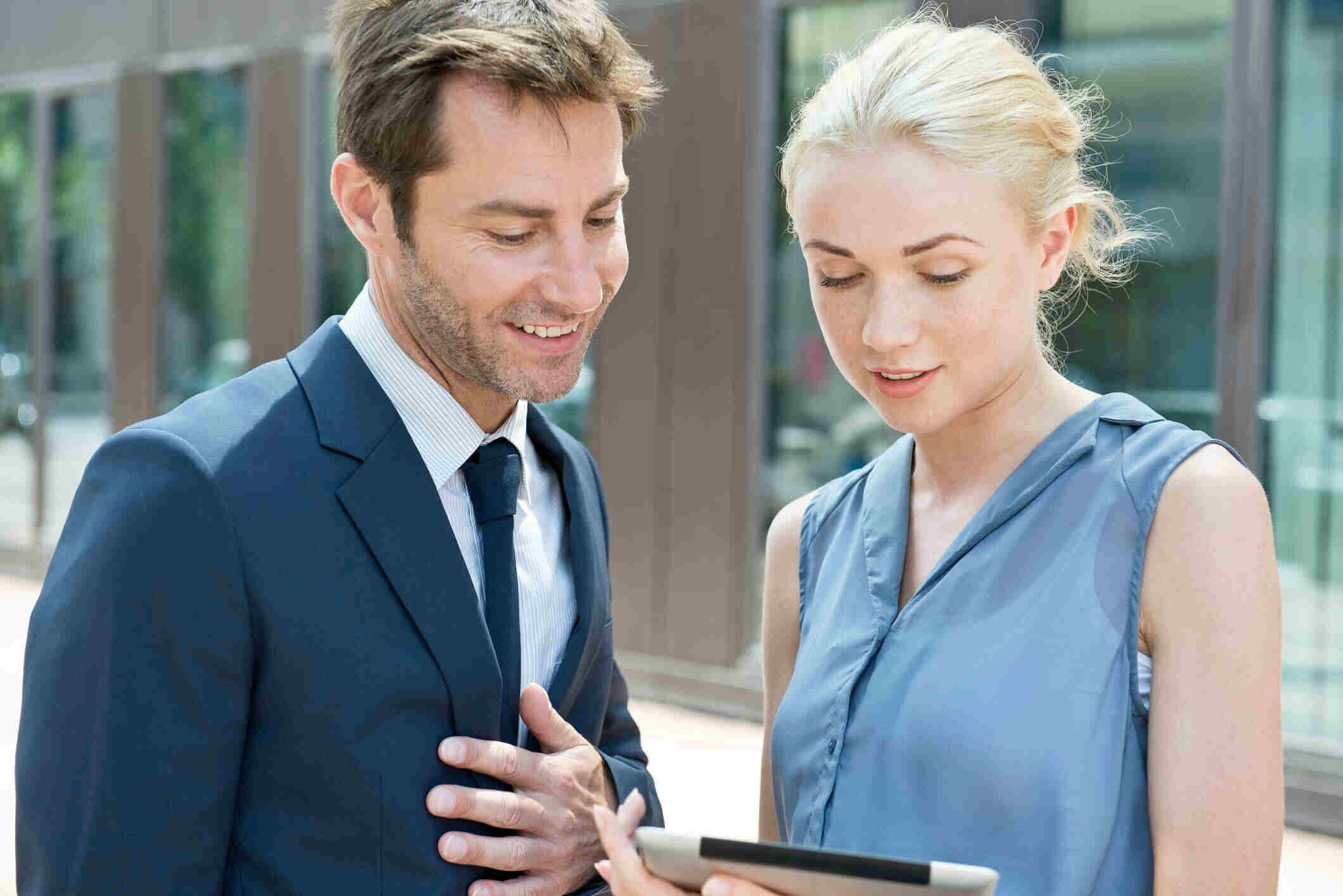 A professional real estate agent in a modern office using a digital tablet to present a commercial lease and property investment data to a client.
