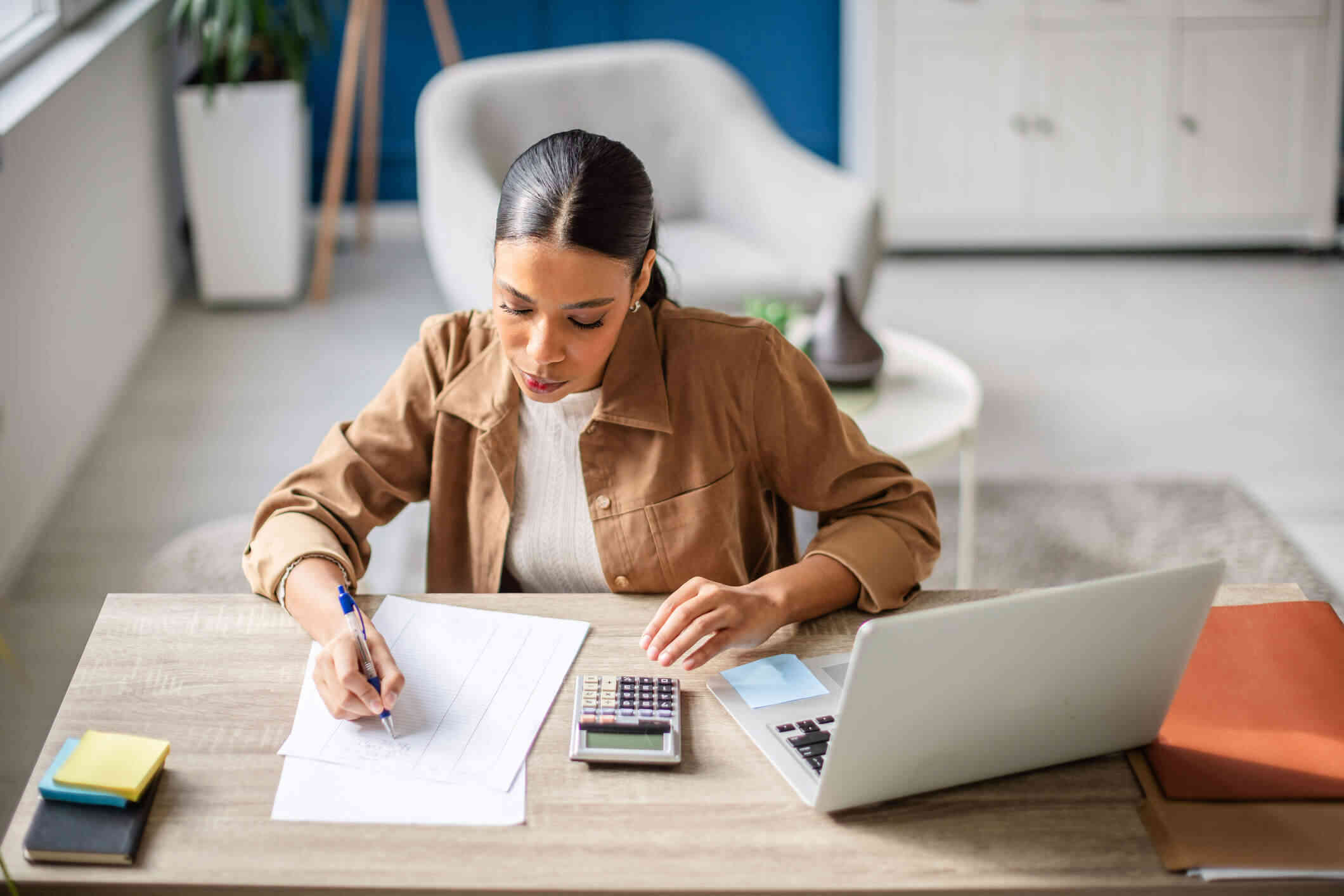 Woman calculating non-resident property tax for Spain at a desk with a calculator, laptop and paperwork