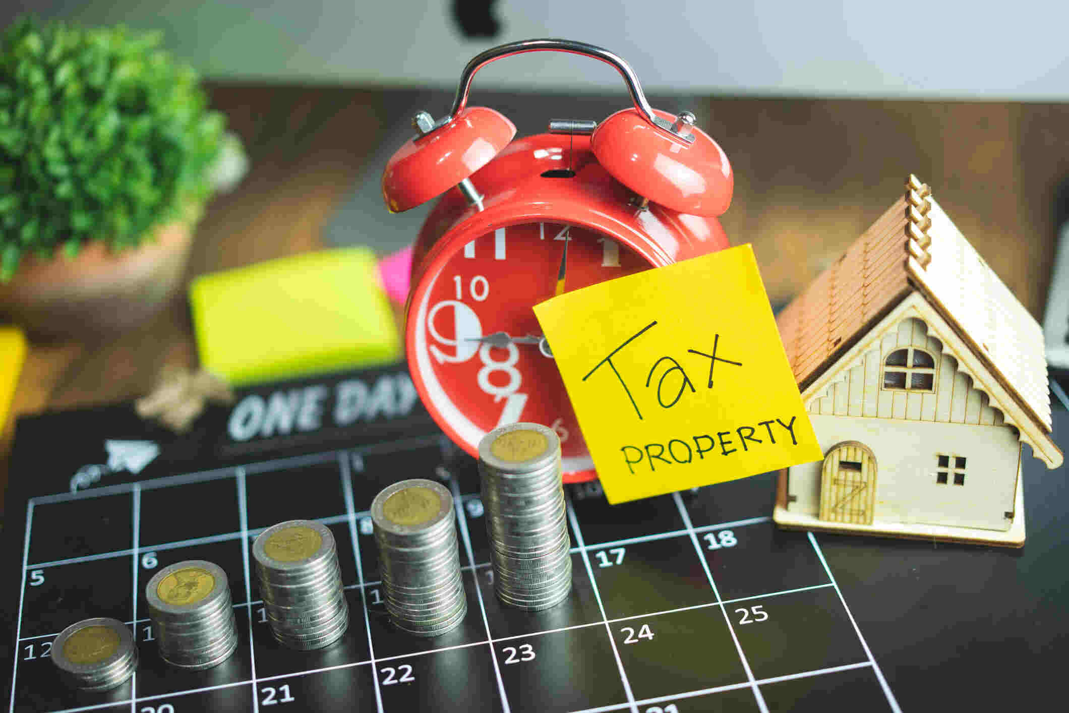 Rental property tax costs and deadlines with coins and a model house