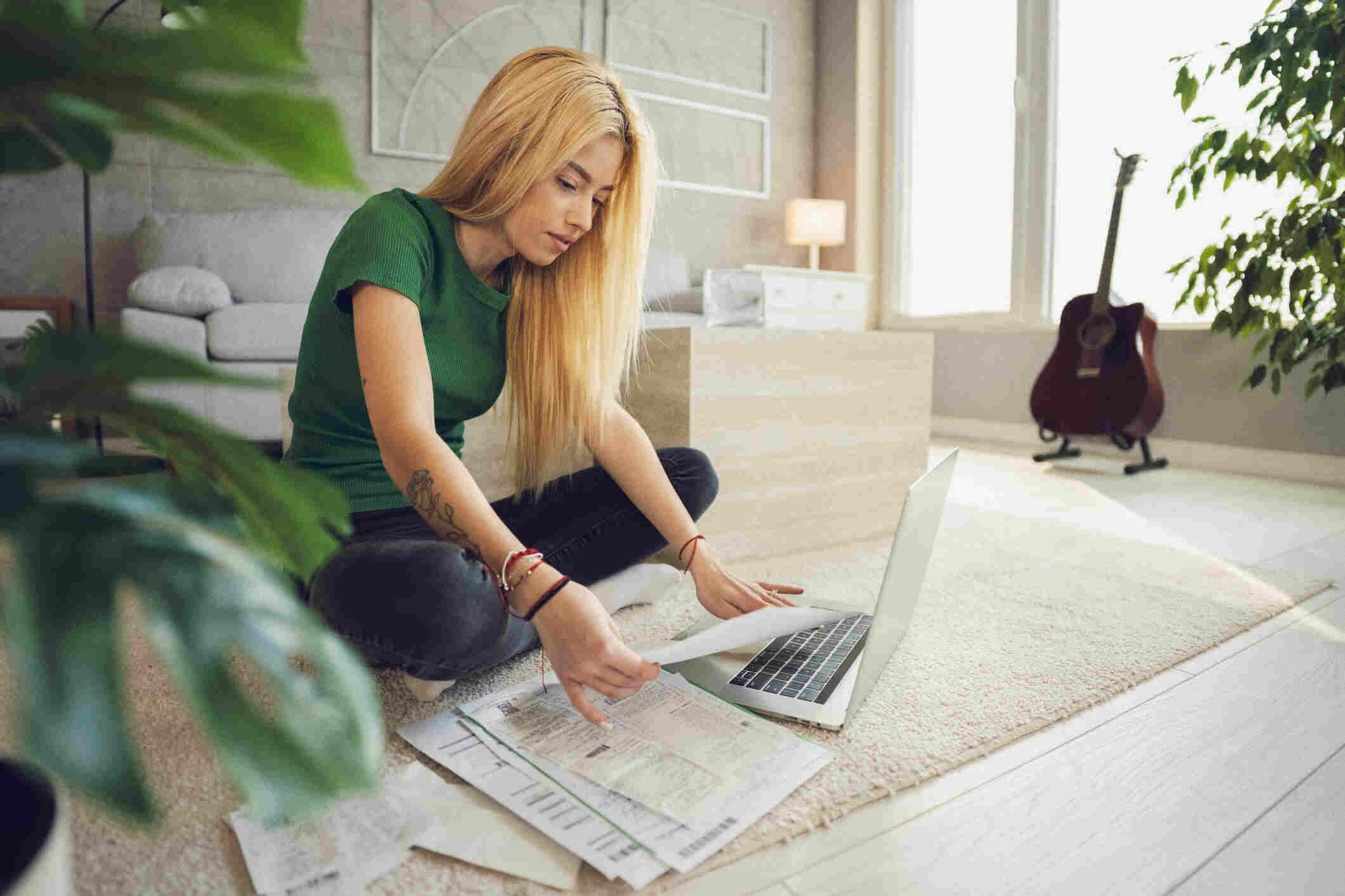 Woman reviewing French property tax documents for non-residents on a living room floor with a laptop
